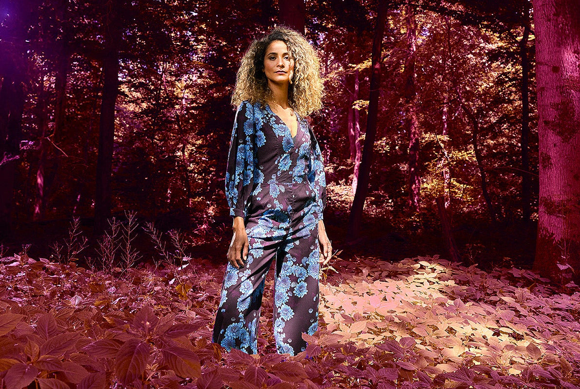 Woman in a jumper standing in a forest with a purple hue