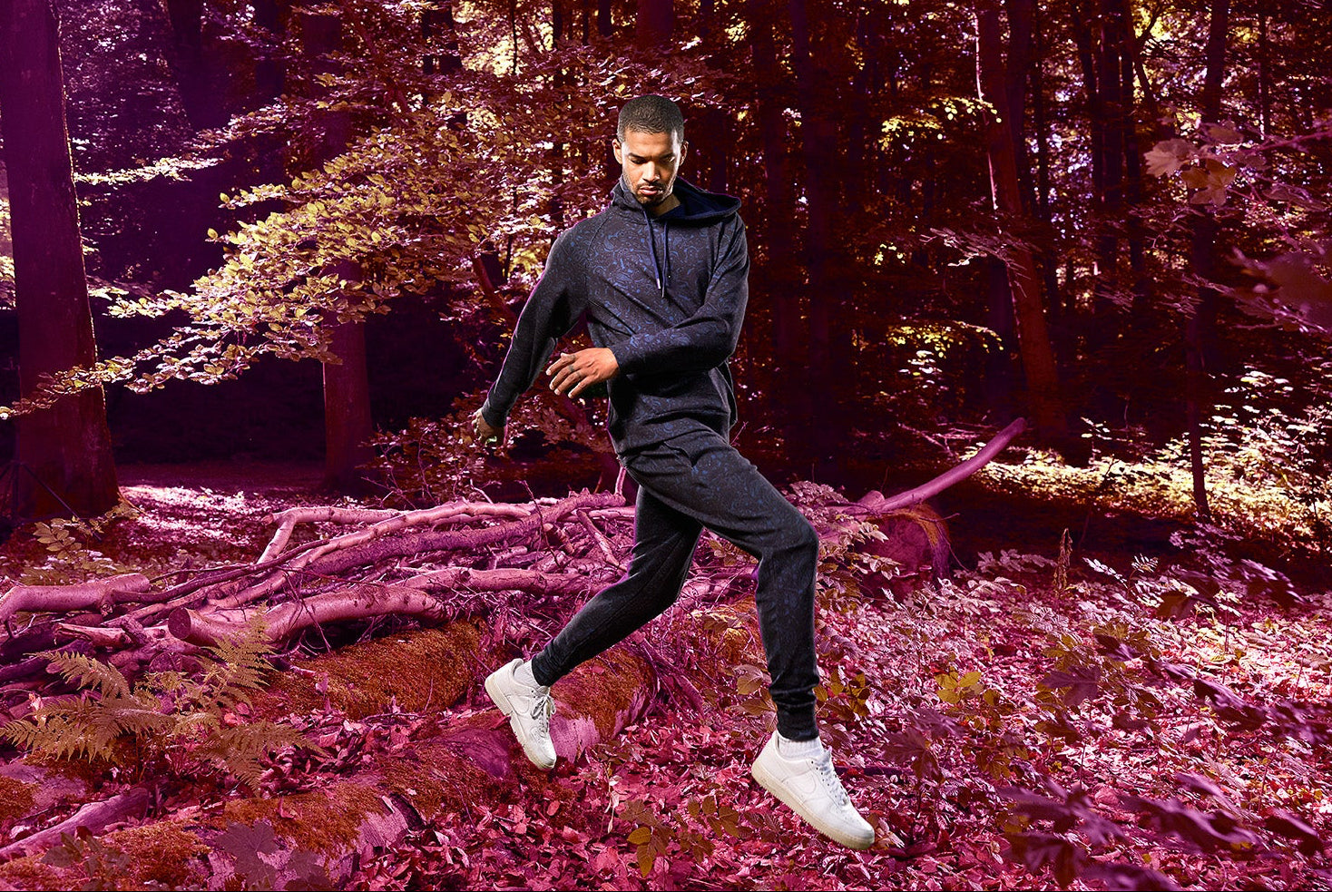 Person running through a forest wearing a paisley hoodie and matching jogger.